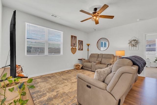 living area with visible vents, ceiling fan, baseboards, and wood finished floors