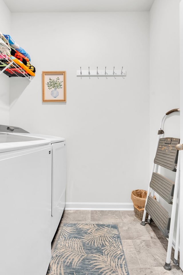 clothes washing area with washer and dryer, laundry area, and baseboards