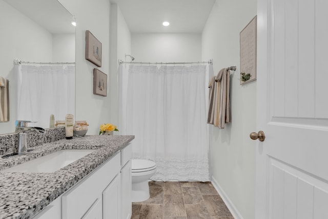 bathroom featuring toilet, stone finish flooring, baseboards, and vanity