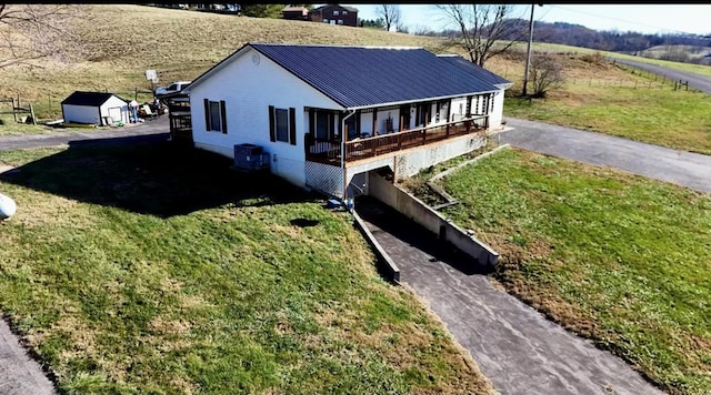 view of front facade with central AC unit, a front lawn, metal roof, and a rural view