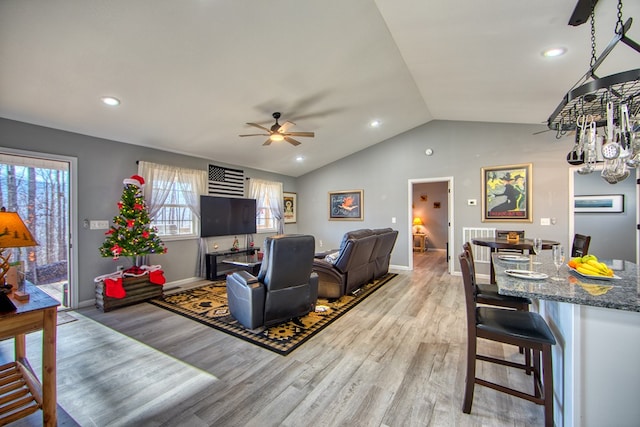 living room with lofted ceiling, light wood-style flooring, and baseboards