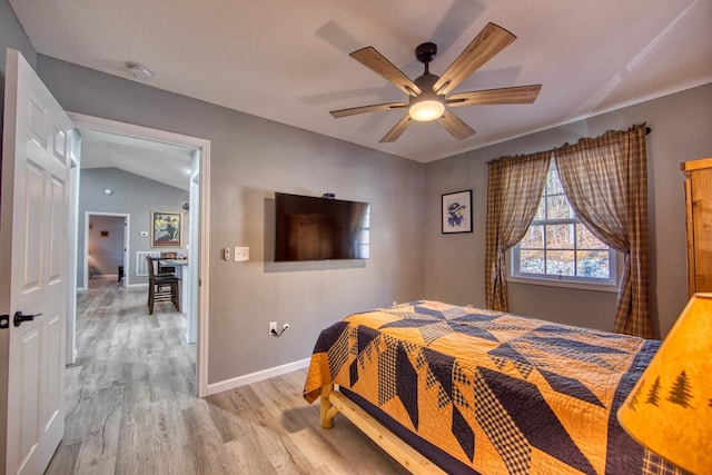 bedroom with vaulted ceiling, light wood finished floors, a ceiling fan, and baseboards