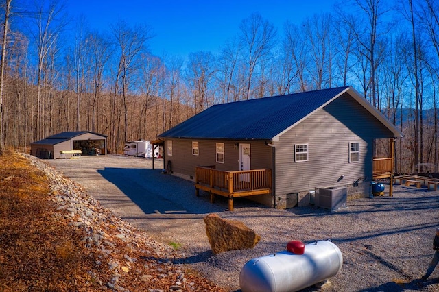 view of front of property with a deck, metal roof, central AC, crawl space, and a view of trees