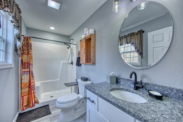 bathroom featuring a stall shower, a textured wall, toilet, wood finished floors, and vanity