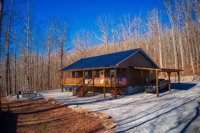 chalet / cabin featuring crawl space, metal roof, a forest view, and a porch