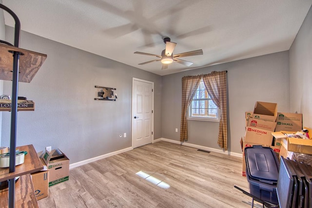 home office featuring ceiling fan, light wood finished floors, visible vents, and baseboards