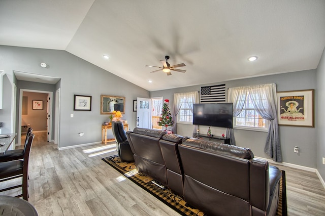 living area with vaulted ceiling, light wood-type flooring, a ceiling fan, and baseboards