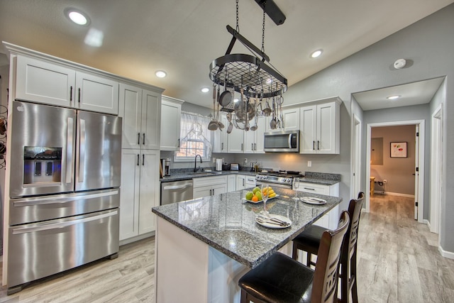 kitchen with stainless steel appliances, stone countertops, white cabinets, and a center island