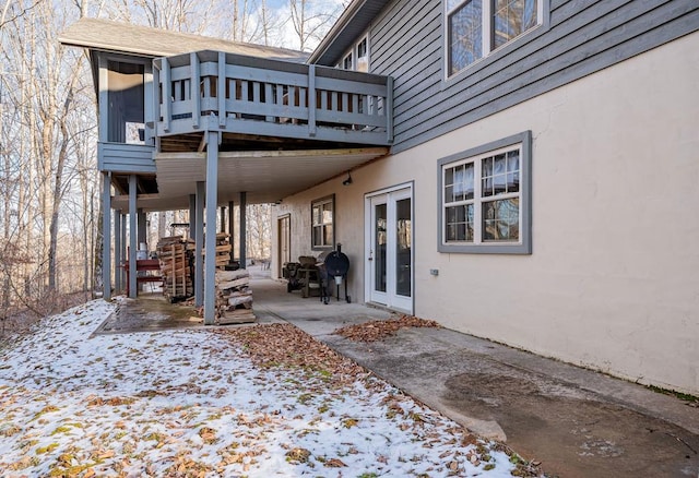 snow covered back of property featuring a patio area and stucco siding