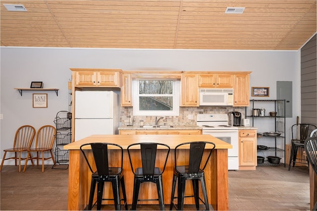 kitchen with white appliances, light brown cabinets, light countertops, and a kitchen breakfast bar