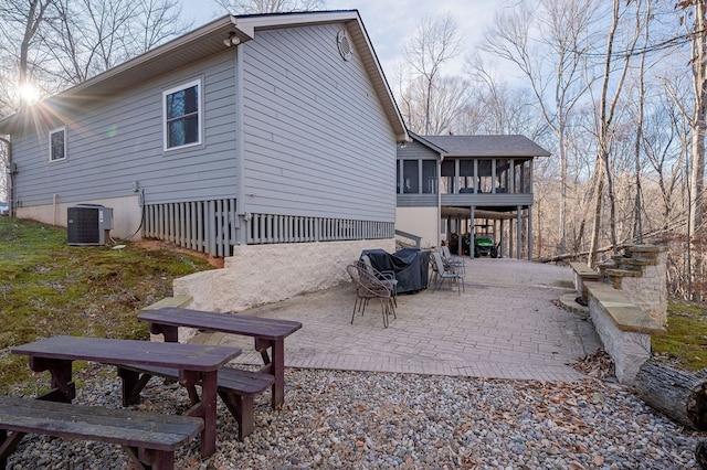 rear view of property with a patio, central AC unit, and a sunroom