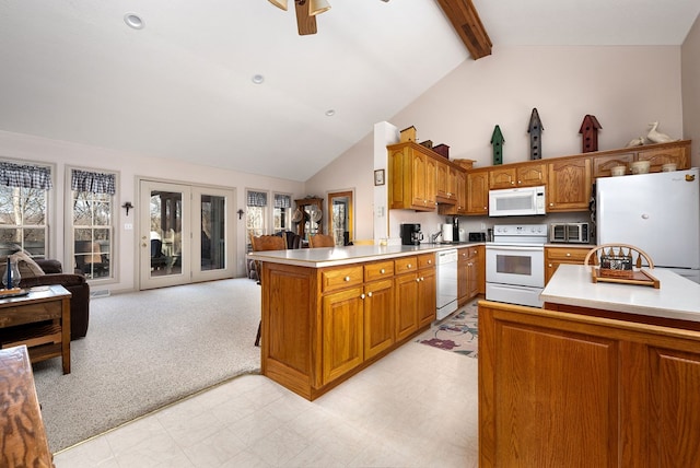 kitchen with a peninsula, white appliances, brown cabinets, and light countertops