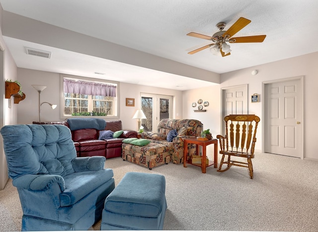 living room featuring light carpet, visible vents, and a ceiling fan