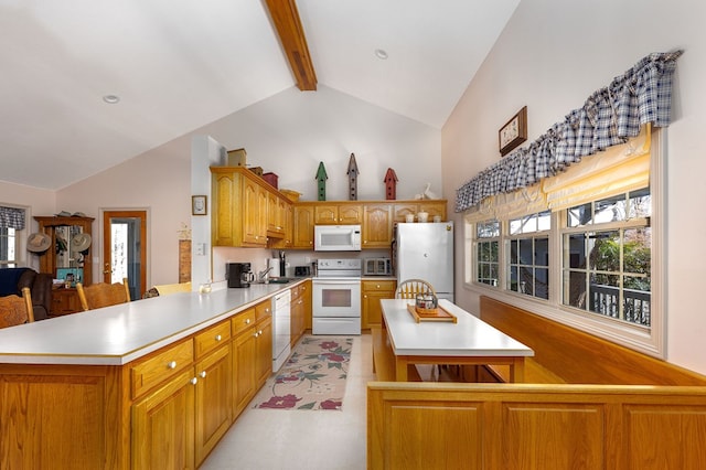 kitchen with a peninsula, white appliances, light countertops, beamed ceiling, and plenty of natural light