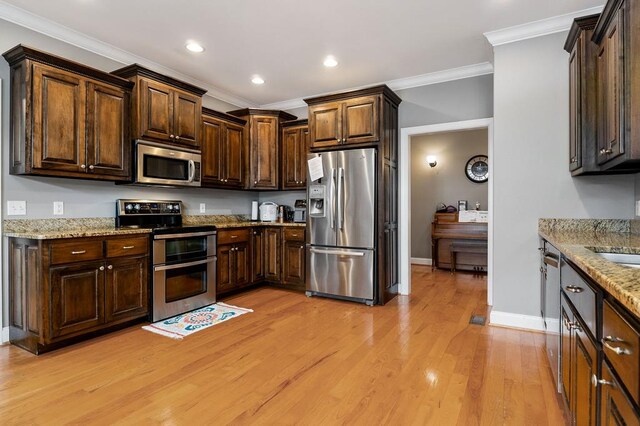 kitchen featuring light stone counters, dark brown cabinetry, appliances with stainless steel finishes, ornamental molding, and light wood finished floors