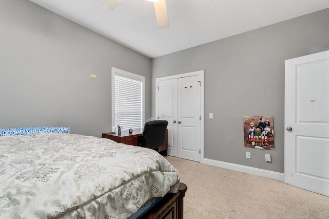 bedroom featuring a ceiling fan, a closet, light colored carpet, and baseboards