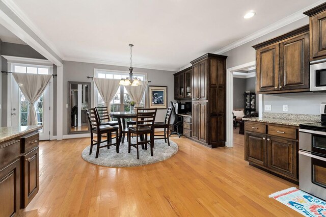 dining space featuring a healthy amount of sunlight, light wood-style floors, and a notable chandelier