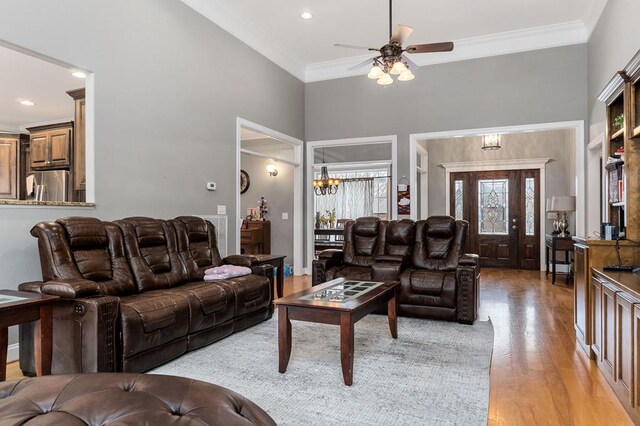 living room with ceiling fan with notable chandelier, crown molding, recessed lighting, and wood finished floors