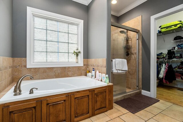 bathroom with a stall shower, ornamental molding, tile patterned floors, a spacious closet, and a bath