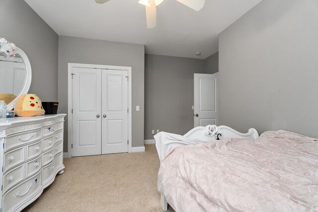 bedroom with a ceiling fan, a closet, light colored carpet, and baseboards