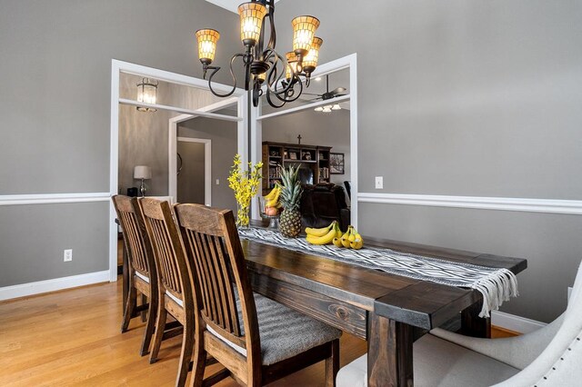 dining area featuring a chandelier, wood finished floors, and baseboards