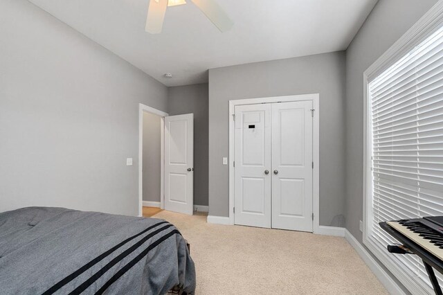 bedroom with ceiling fan, baseboards, a closet, and light colored carpet