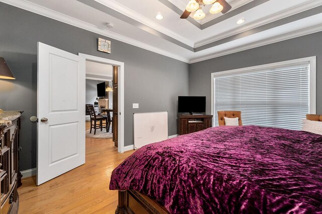 bedroom with baseboards, a tray ceiling, crown molding, light wood-type flooring, and recessed lighting