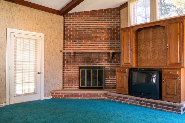 unfurnished living room with beam ceiling, a fireplace, carpet flooring, and a wealth of natural light