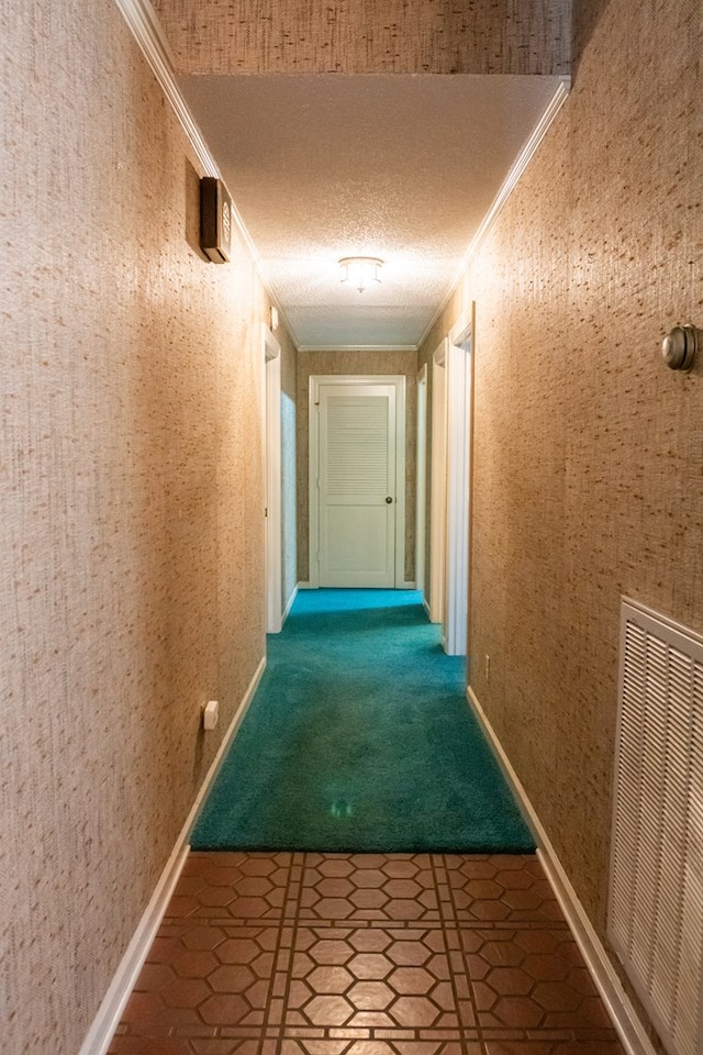 hallway with visible vents, crown molding, a textured ceiling, and wallpapered walls