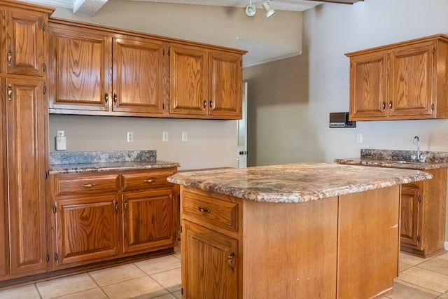 kitchen with brown cabinetry, light countertops, a sink, and a center island