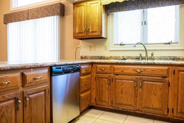 kitchen with brown cabinets, light countertops, light tile patterned flooring, a sink, and dishwasher