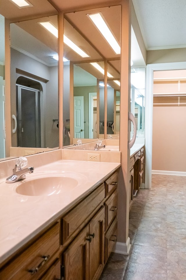 bathroom featuring a shower stall, baseboards, crown molding, and vanity