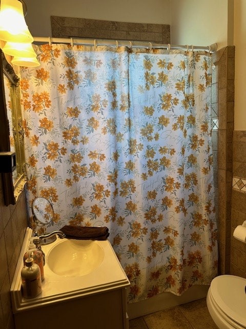 bathroom featuring tile patterned flooring, toilet, vanity, tile walls, and shower / bath combination with curtain