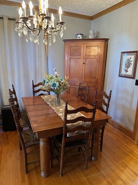 dining room featuring ornamental molding, light wood-style flooring, a textured ceiling, and baseboards