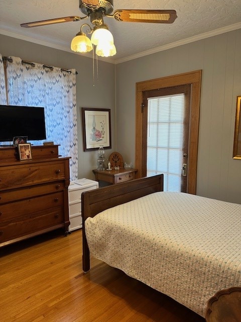 bedroom with ornamental molding, light wood-style floors, a textured ceiling, and ceiling fan