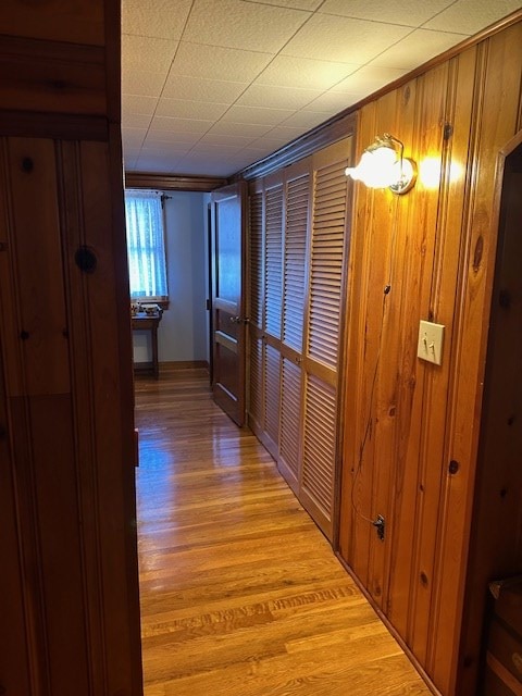 hall featuring light wood-style flooring and wooden walls