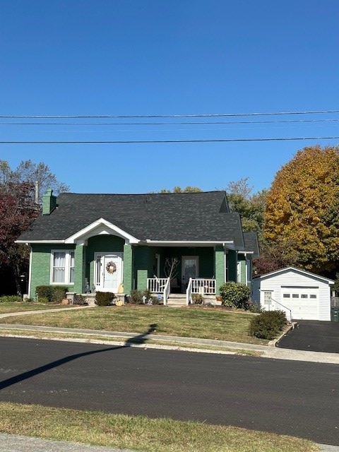 view of front of property with a garage, aphalt driveway, covered porch, an outdoor structure, and a front lawn