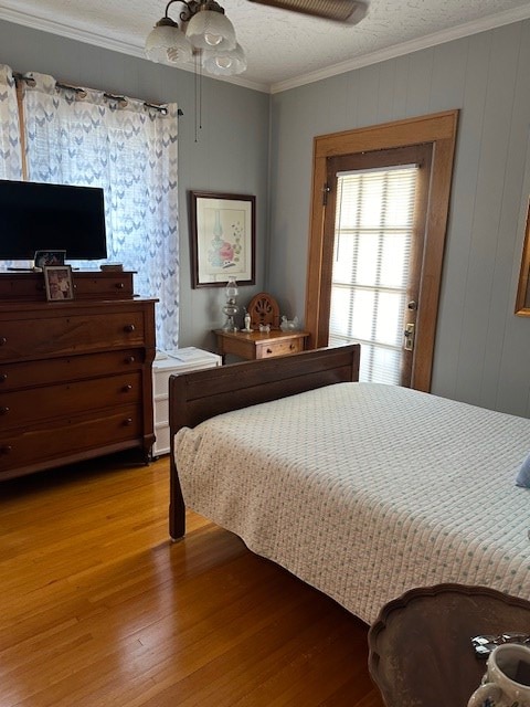 bedroom with a textured ceiling, ceiling fan, light wood-type flooring, and crown molding