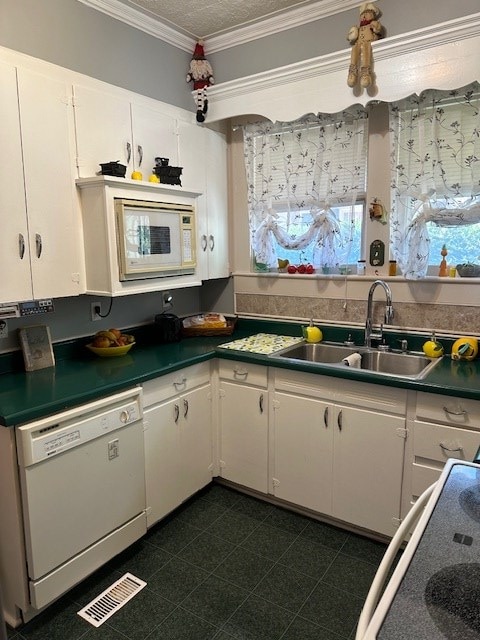 kitchen with white appliances, visible vents, dark countertops, white cabinetry, and a sink