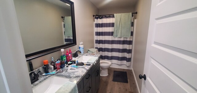 full bathroom with double vanity, a sink, toilet, and wood finished floors