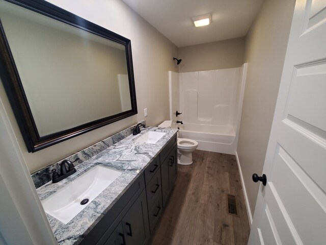 bathroom with double vanity, visible vents, a sink, and wood finished floors