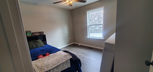 bedroom with ceiling fan, baseboards, and wood finished floors