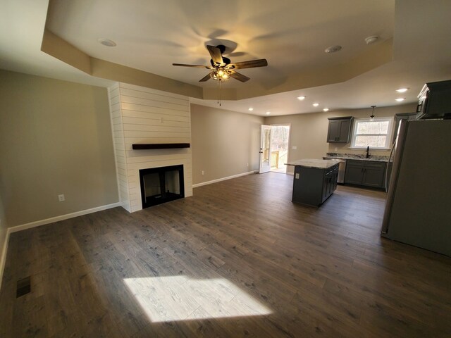 unfurnished living room featuring a fireplace, baseboards, dark wood-type flooring, and recessed lighting