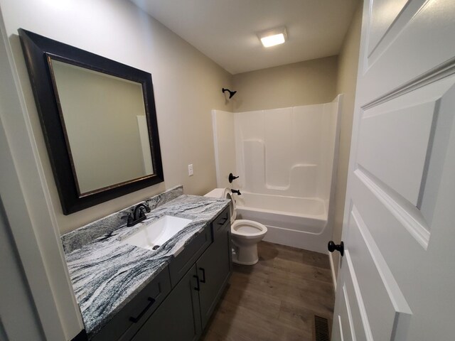 bathroom featuring visible vents, toilet, wood finished floors, tub / shower combination, and vanity