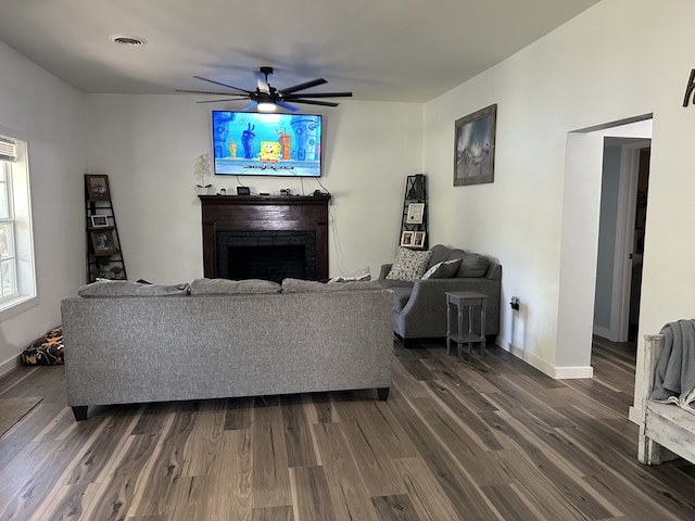 living room with baseboards, a fireplace, a ceiling fan, and dark wood-type flooring