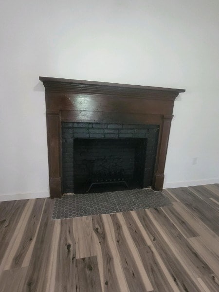 room details with a fireplace with flush hearth, baseboards, and wood finished floors