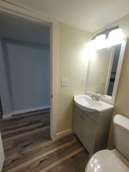 bathroom with toilet, wood finished floors, vanity, and baseboards