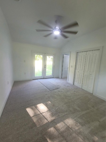 interior space featuring carpet, french doors, lofted ceiling, a ceiling fan, and baseboards