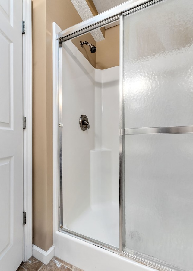 bathroom with a shower with shower door and baseboards