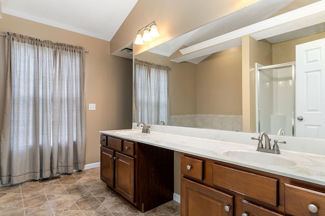 full bath featuring a stall shower, lofted ceiling, a sink, and double vanity